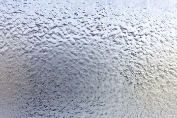 a frosted glass texture with subtle ice patterns forming across the surface, captured in soft, diffused light to highlight the cool elegance of the material.