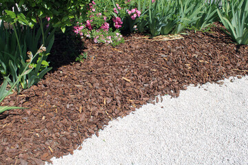Paillage d'un massif de jardin avec des copeaux de bois et bordure en gravier blanc