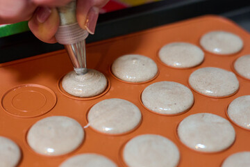 Preparing homemade french macarons. Piping batter with a pastry bag fitted with a round tip