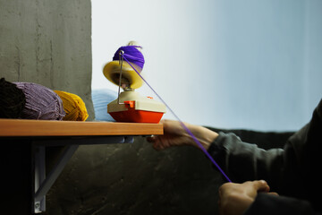 Part of craftswoman rolling yarns on ball winder
