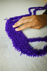 Close up of craftswoman checking thread on canvas while making rug