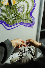 Part of craftswoman pulling thread from rug tufting machine
