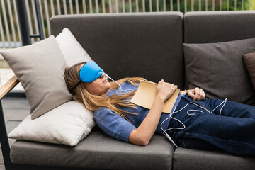 Woman sleeping with temperature controlled sleep mask and book on chest