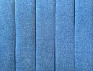 Close up of blue cushion upholstered panel, or a padded wall. Blue fabric upholstery suitable for sofa, soft seating, and bed headboard. Seamless background texture. 