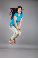A young woman confidently poses wearing blue t-shirt, distressed denim jeans, heels, showcasing a casual urban style with charm and elegance, suitable for haircare, freedom, self-expression project