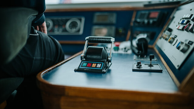 Cargo barge navigating river with mooring ropes and control panel detail