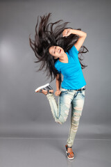 A young woman confidently poses wearing blue t-shirt, distressed denim jeans, heels, showcasing a casual urban style with charm and elegance, suitable for haircare, freedom, self-expression project