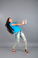 A young woman confidently poses wearing blue t-shirt, distressed denim jeans, heels, showcasing a casual urban style with charm and elegance, suitable for haircare, freedom, self-expression project