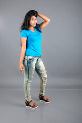 A young woman confidently poses wearing blue t-shirt, distressed denim jeans, heels, showcasing a casual urban style with charm and elegance, suitable for haircare, freedom, self-expression project