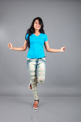 A young woman confidently poses wearing blue t-shirt, distressed denim jeans, heels, showcasing a casual urban style with charm and elegance, suitable for haircare, freedom, self-expression project
