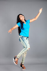 A young woman confidently poses wearing blue t-shirt, distressed denim jeans, heels, showcasing a casual urban style with charm and elegance, suitable for haircare, freedom, self-expression project
