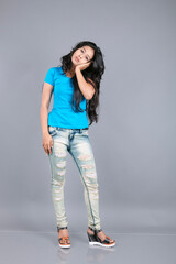 A young woman confidently poses wearing blue t-shirt, distressed denim jeans, heels, showcasing a casual urban style with charm and elegance, suitable for haircare, freedom, self-expression project