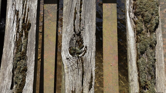 Old wooden plank construction with moss alternating with rusty metal profiles