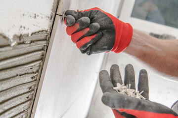 Worker Using Tools to Attach Tiles to a Wall in a Construction Site