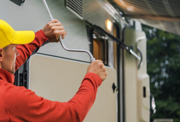 Man Adjusting the Awning of an RV in a Cozy Outdoor Campsite During the Afternoon