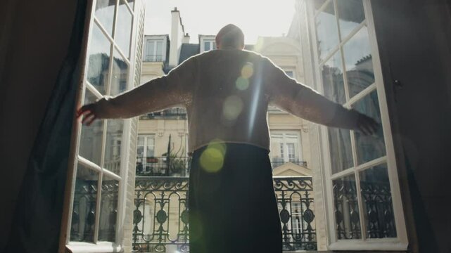 Man opening french window in paris apartment, welcoming new day