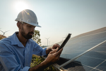 Young Asian engineer with beard inspects solar panels with tablet, renewable energy for the future concept