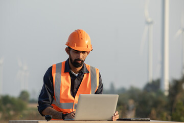 Young Engineer or Maintenance Technician Working with Laptop Computer on Wind Farm