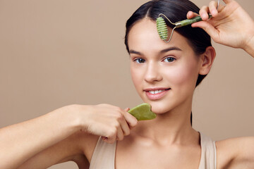 A young woman with a serene expression uses a jade roller and gua sha stone on her face, promoting healthy skincare routines and natural beauty