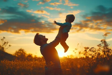 A silhouette of a father holding his child up in the air during a vibrant sunset in a field