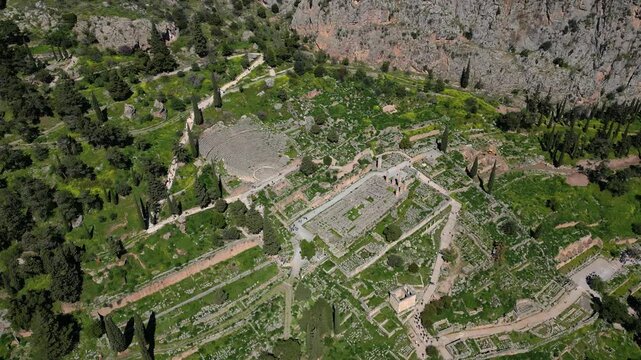 Drone establishing of ancient amphitheater at Delphi with stone ruins and trees surrounding