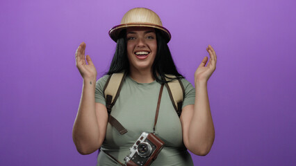 Smiling woman with dark hair wearing explorer hat and holding vintage camera, appearing excited...