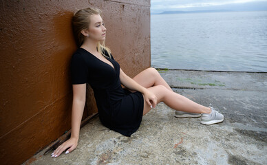Woman in a black dress enjoys herself at the seashore.