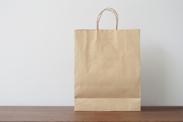 Blank brown paper bag on wooden table. Mockup for you designs.