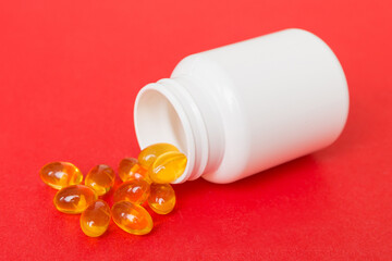 Omega-3 capsules lie in white bottle on a table background. Fish oil tablets top view. Biologically...