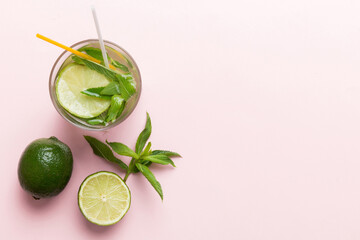 Caipirinha, Mojito cocktail, vodka or soda drink with lime, mint and straw on table background. Refreshing beverage with mint and lime in glass top view flat lay