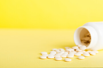 Medicine bottle and white pills spilled on a light background. Medicines and prescription pills flat lay background. White medical pills and tablets spilling out of a drug bottle