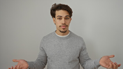 Young man with expressive look standing against isolated white background wearing gray shirt...