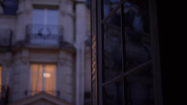 Parisian building seen through window at dusk