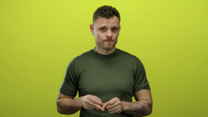 Young hispanic man in green shirt against isolated yellow background appears pensive showing...