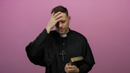 Priest holding bible and touching forehead in thought against pink background