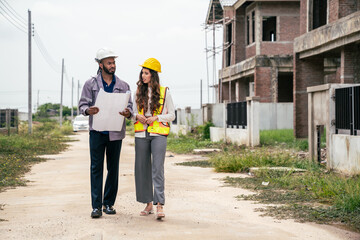 Black Male Construction Engineer Holding Blueprint Walks on Housing Project Site Focused on Inspection, Planning, and Development