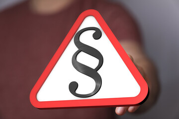 Hand holding a red triangle warning sign with a paragraph symbol.  Legal, law, caution concept.