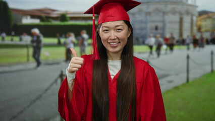 Woman in red graduation gown pointing with pisa tower in italy in the background