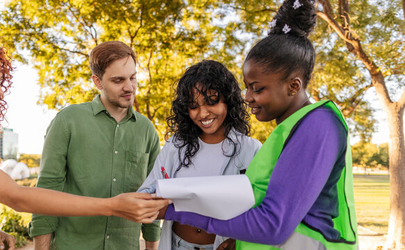 Volunteers reading and signing a petition in a park