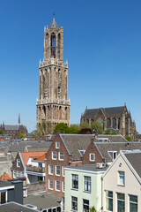 Iconic Dom Tower and Dom Church rise above Utrecht's rooftops under a clear blue sky, showcasing Dutch heritage.