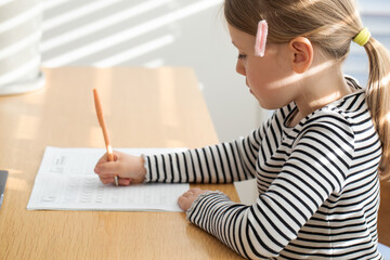 Young girl practicing writing with focus in sunlit room