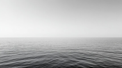 Minimalist black and white photography of a calm sea merging with the clear sky, creating a serene and peaceful atmosphere