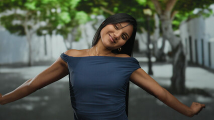 Fototapeta premium Young woman smiling joyfully in a peaceful street with trees creating a serene outdoor atmosphere, embracing a moment of happiness and tranquility.