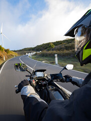 Driver riding motorcycle on empty asphalt road, handlebars view , spring mountains