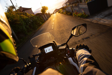 Driver riding motorcycle on empty asphalt road, handlebars view , spring mountains