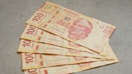 Mexican 100 pesos banknotes laid out on concrete background illustrating currency and finance...