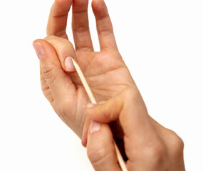 Female hands using wooden cuticle stick on white background