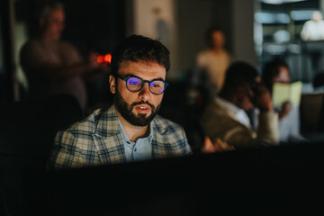 Business professional intensely concentrating on a computer screen, working late in a dim office....