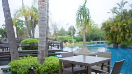 Blurred view of a luxurious tropical resort with a defocused outdoor poolside setting featuring palm trees and elegant furniture, evoking a serene vacation atmosphere.