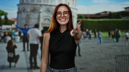Woman smiling extends hand with pisa tower in background surrounded by visitors in outdoor setting in italy.